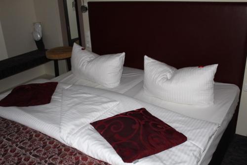 a bed with white sheets and pillows on it at Hotel Schmuckkästchen in Miltenberg