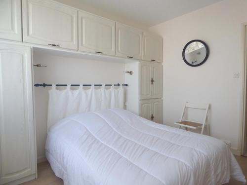 una camera da letto con un letto bianco e un orologio sul muro di La Houle a Saint-Gilles-Croix-de-Vie
