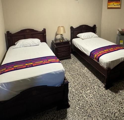 1 dormitorio con 2 camas y una lámpara en una mesa en Hostal La Casta en Camarones