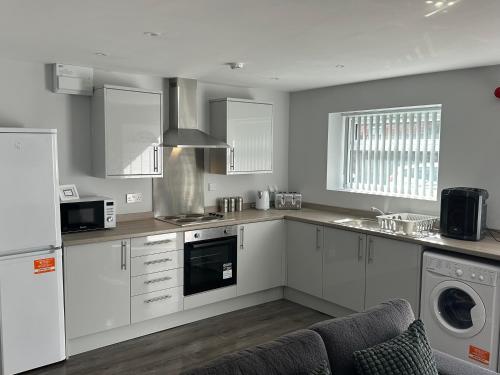 a kitchen with white cabinets and a washer and dryer at Smeaton serviced Accommodation in Liverpool