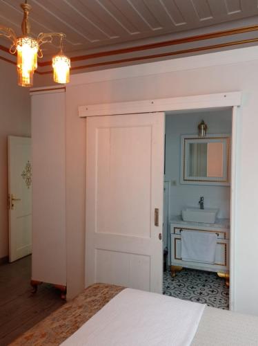 1 dormitorio con puerta blanca y lavamanos en BUDAKZADE KONAĞI OTEL-RESTAURANT 1841 en Karşıyaka