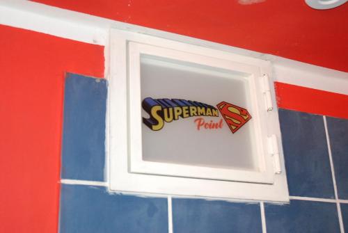 a window in a wall with a superman punch sign at Comics Factory Airport & City in Catania