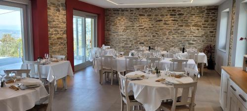 a restaurant with white tables and chairs and a brick wall at Agriturismo Le Arcate in Sinio