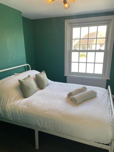 1 dormitorio con 1 cama con 2 almohadas y ventana en Cozy Town House en Lewes
