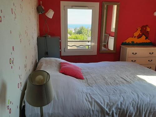 ein rotes Schlafzimmer mit einem Bett und einem Fenster in der Unterkunft Jolie villa provençale avec piscine et vue mer in La Ciotat