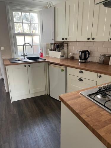 a kitchen with white cabinets and a sink at Cozy Town House in Lewes
