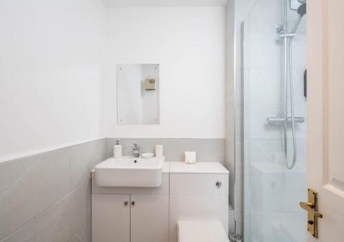 a white bathroom with a sink and a shower at Crawley Maunsell Park Charm & Cosy 1 Bedroom Apartment with Parking in Crawley