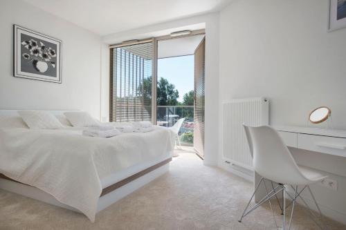 a white bedroom with a bed and a desk and a chair at Apartament Premium PINEA 102 in Pobierowo