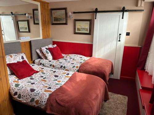 - 2 lits dans une petite chambre aux murs rouges dans l'établissement Seaview Cottage 24 Freeman Street, à Wells-next-the-Sea
