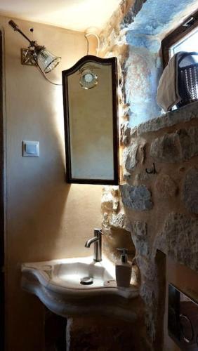Baño de piedra con lavabo y espejo en Studio Tsiliviani, en Loukádhika