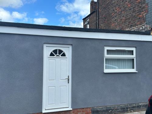 a gray house with a white door and two windows at Smeaton serviced Accommodation in Liverpool