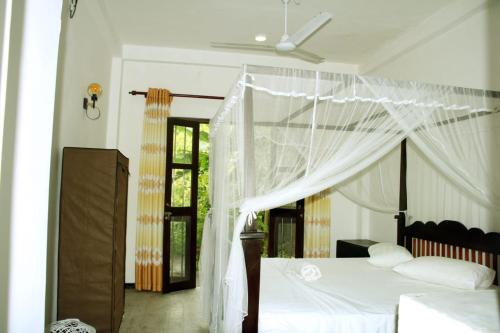 - une chambre avec un lit à baldaquin dans l'établissement Lion House, à Galle