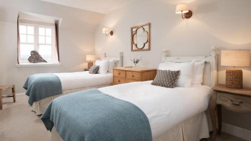 a bedroom with two beds and a mirror on the wall at The Coach House, Pentland Hills in Nine Mile Burn