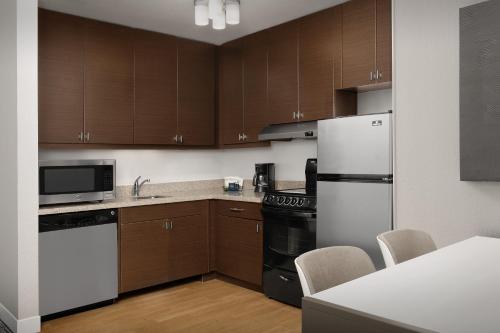a kitchen with wooden cabinets and a white refrigerator at TownePlace Suites by Marriott Cheyenne Southwest/Downtown Area in Cheyenne