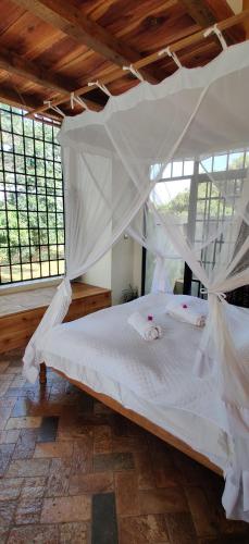 a bedroom with a large white bed with mosquito nets at Harry's Cabin - Overlooking Lake Victoria - 30 min from Jinja in Jinja