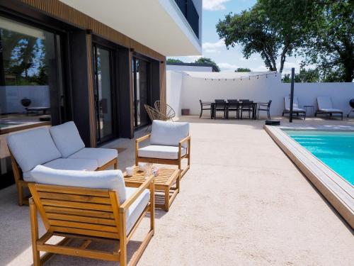 a patio with chairs and a table and a pool at Beautiful Villa close to the Seaside in Talmont