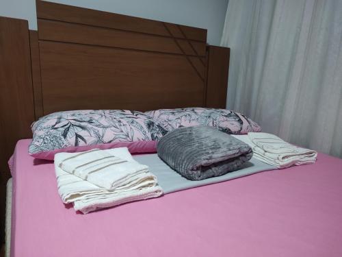 a bed with two folded towels on a pink bed at Casa de 3 quartos in Resende