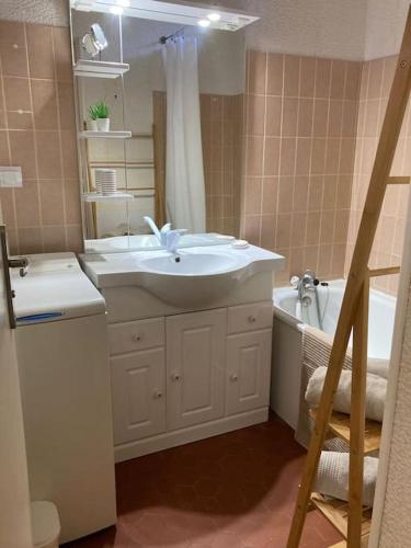 une salle de bain avec un lavabo, une baignoire et un miroir dans l'établissement Maison au calme dans la pinède, à Lacanau