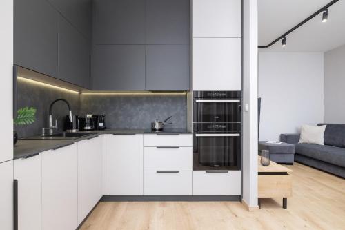 a kitchen with white cabinets and stainless steel appliances at Bright Apartment in Kraków with Garden, Air Conditioning, Parking and Desk by Renters Prestige in Kraków