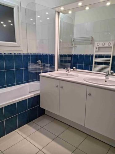 une salle de bain avec deux lavabos, un miroir et une baignoire dans l'établissement Appartement avec piscine - 6494, à Soulac-sur-Mer