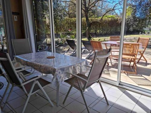 une table et des chaises en verre sur la terrasse dans l'établissement Appartement avec piscine - 6494, à Soulac-sur-Mer