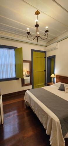 um quarto com uma cama grande e um lustre em Pousada Laços de Minas em Ouro Preto