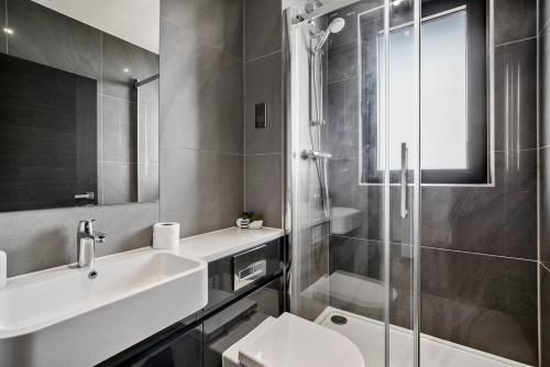 La salle de bains est pourvue d'un lavabo, de toilettes et d'une douche. dans l'établissement Stylish Gem Of Chelmsford with Balcony, à Chelmsford