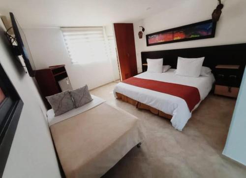 una camera d'albergo con due letti e un divano di Hotel Alessio a Bucaramanga