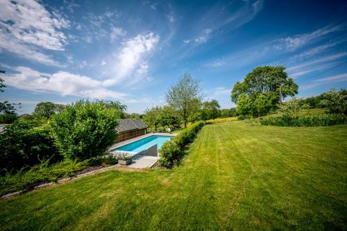 un patio trasero con piscina y césped en Vakantiewoning De Woestijn, en Roosdaal