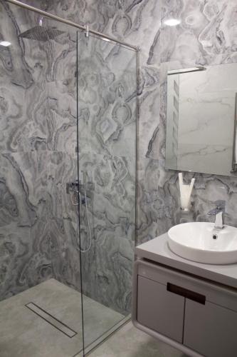a bathroom with a glass shower and a sink at Lux Plaza Hotel EVN airport in Arbatʼ