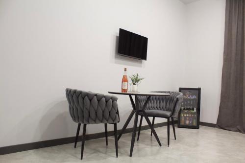 a dining room table with two chairs and a bottle of wine at Lux Plaza Hotel EVN airport in Arbatʼ