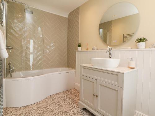 a bathroom with a sink and a tub and a mirror at Applestow in Bideford