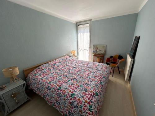 a bedroom with a bed with a colorful bedspread and a window at Calme et vue exceptionnelle! in Banyuls-sur-Mer