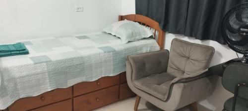 a bedroom with a bed and a chair and a fan at Pousada da Vila 1 in Araçariguama