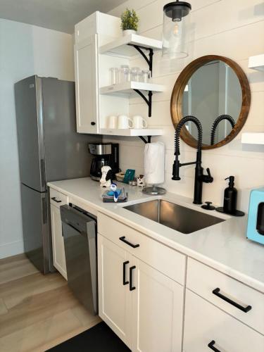 a kitchen with a sink and a stainless steel refrigerator at Cracker Cow Cottages - Cottage B in Fort Myers