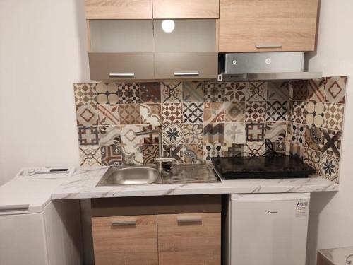 a kitchen with a sink and a tile wall at Οrantes Maris Family And Groups in Katapola