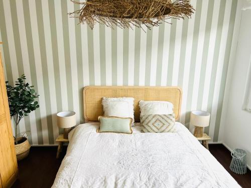 ein Bett mit weißen Laken und Kissen in einem Schlafzimmer in der Unterkunft La casa magique, bulle enchantée, 100m de la plage in Andernos-les-Bains