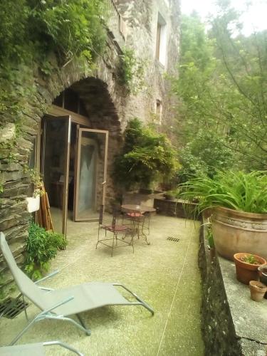 a patio with a table and chairs in a stone building at Le mas des sources cevenol Le chambon in Le Chambon