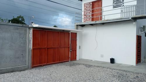 uma garagem com uma porta vermelha ao lado de uma casa em HOSTAL SALINAS HOUSE em Salinas
