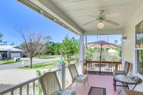 a porch with chairs and a table and an umbrella at Lovely Carrabelle Home with Lake Views and Pool Access in Carrabelle