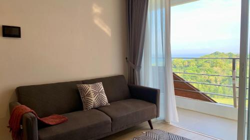 a living room with a couch and a large window at Two Bedroom Apartment at The Nove, Nuvasa Bay, Nongsa 719 in Nongsa