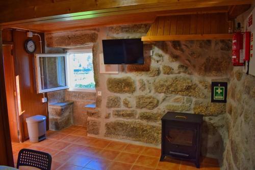 a room with a stone wall with a stove at Casa Ti' Beites, no Santuário de Nossa Senhora da Peneda in Arcos de Valdevez
