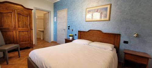 a bedroom with a white bed and a blue wall at Agriturismo Le Arcate in Sinio