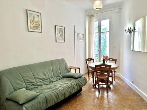un salon avec un canapé vert et une table dans l'établissement Cannes La Croisette - Studio au calme coté jardin, à Cannes