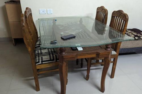 een glazen tafel met twee stoelen en een mobiele telefoon erop bij Sree Sai Guruvayoor in Guruvāyūr