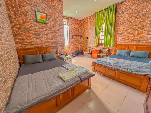 a bedroom with two beds and a brick wall at Hoàng Sơn's Home in Can Tho