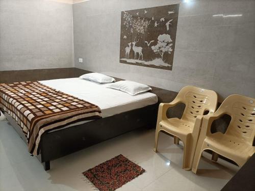 a bedroom with a bed and two chairs in it at Hillview Cottage in Kuttālam