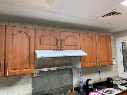 a kitchen with wooden cabinets and a white range hood at Stanley Hostel in Dubai