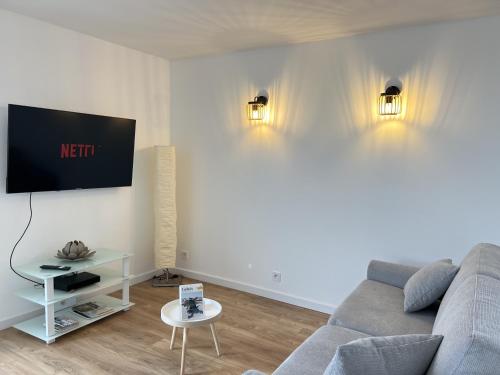 un salon avec un canapé et une télévision sur un mur dans l'établissement L'Escale Calaisienne, à Calais