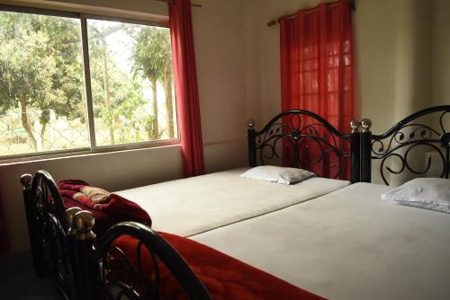 2 Betten in einem Schlafzimmer mit Fenster in der Unterkunft Dooars Nest Resort Rahutbari in Chālsa Mahābāri